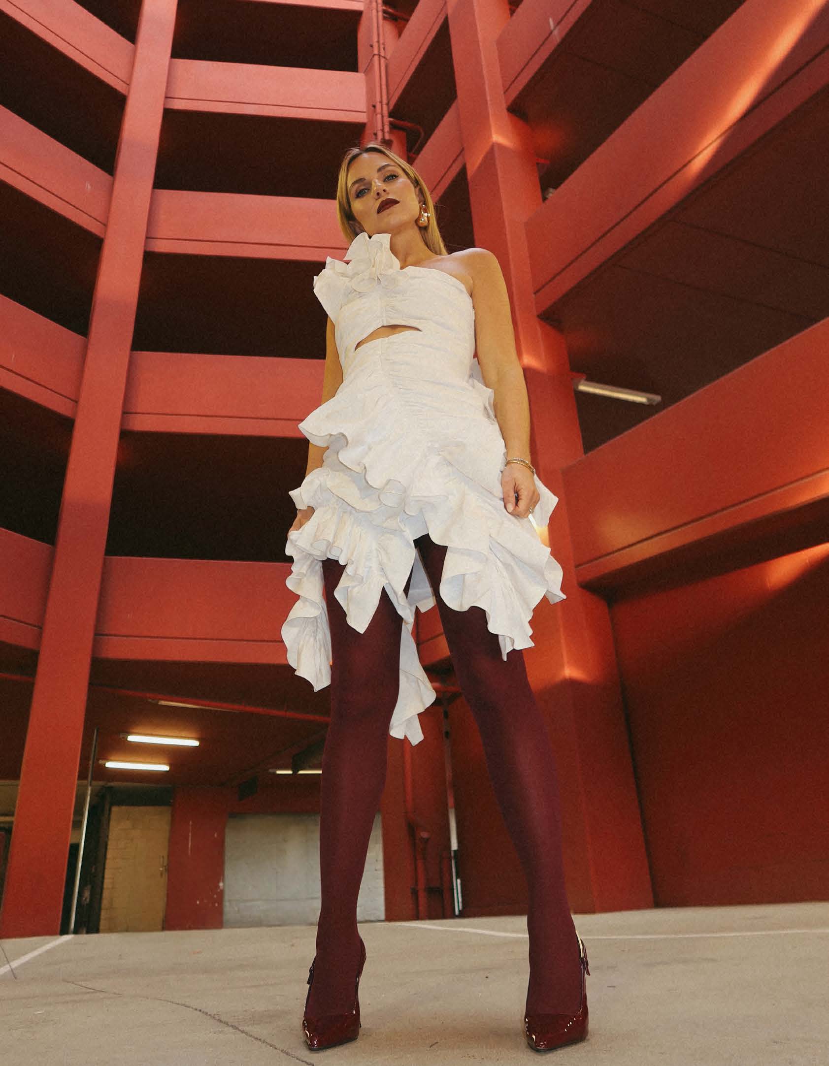 Jeanna Kotenko in a white dress against red architecture